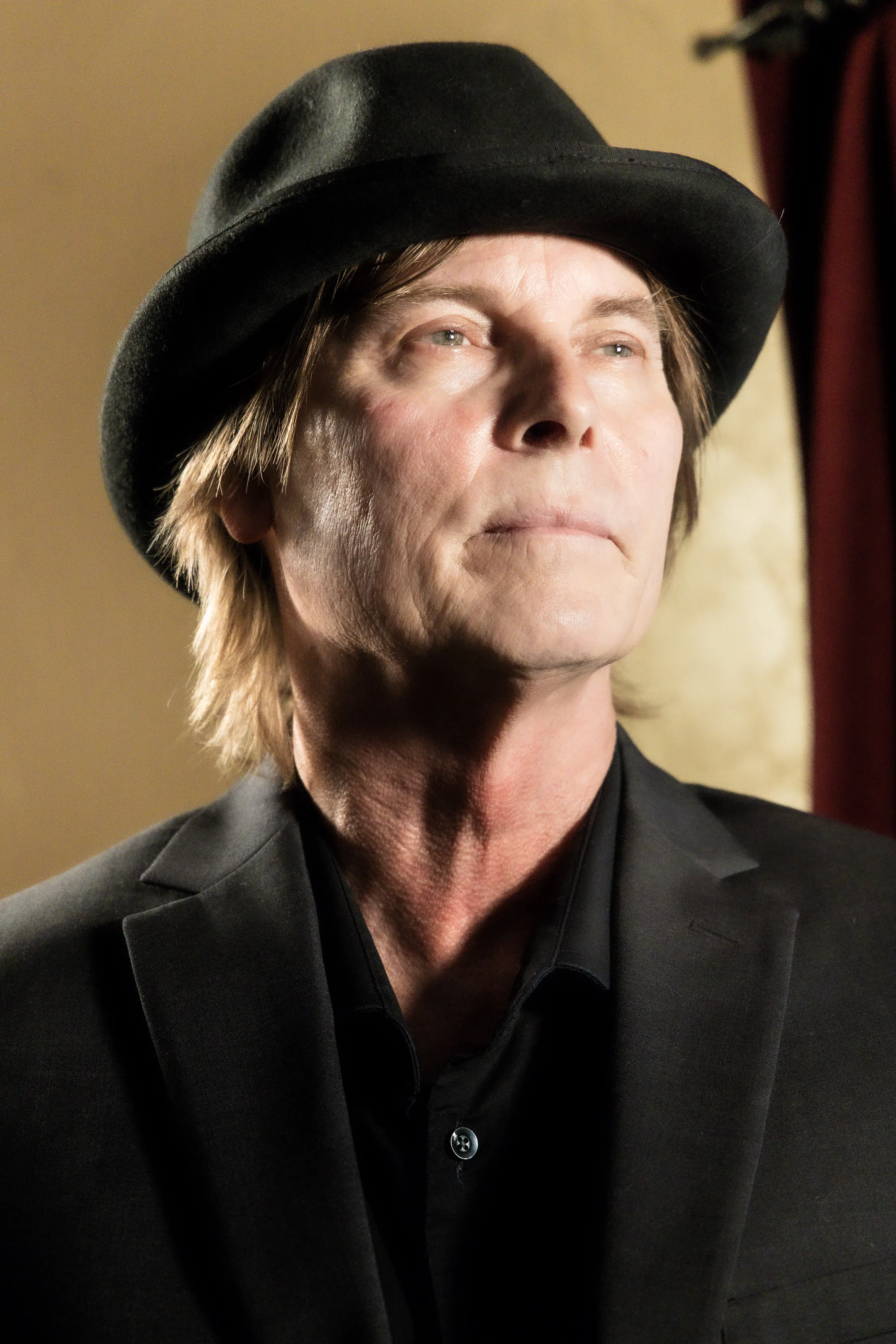 Close-up portrait of a costumed performer in a dark coat and black hat.