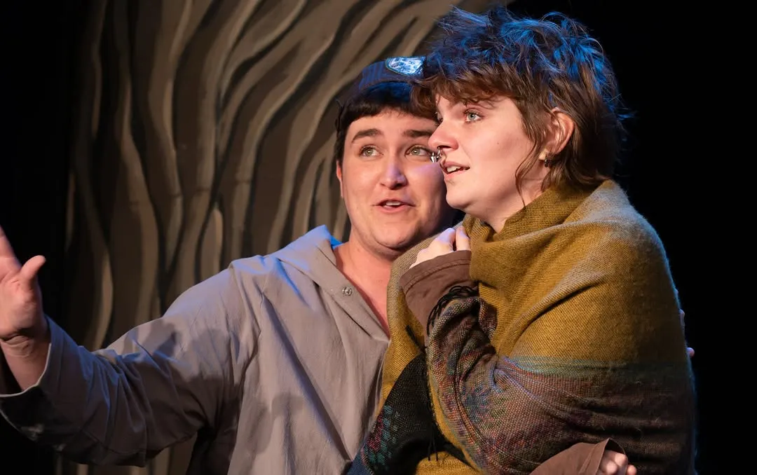 Two Tragedians exchange exaggerated expressions in a close-up.