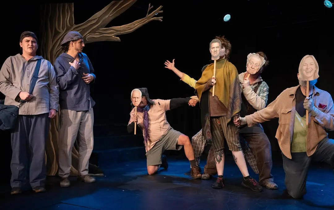 The Tragedians spread across the stage, gesturing with outstretched arms.