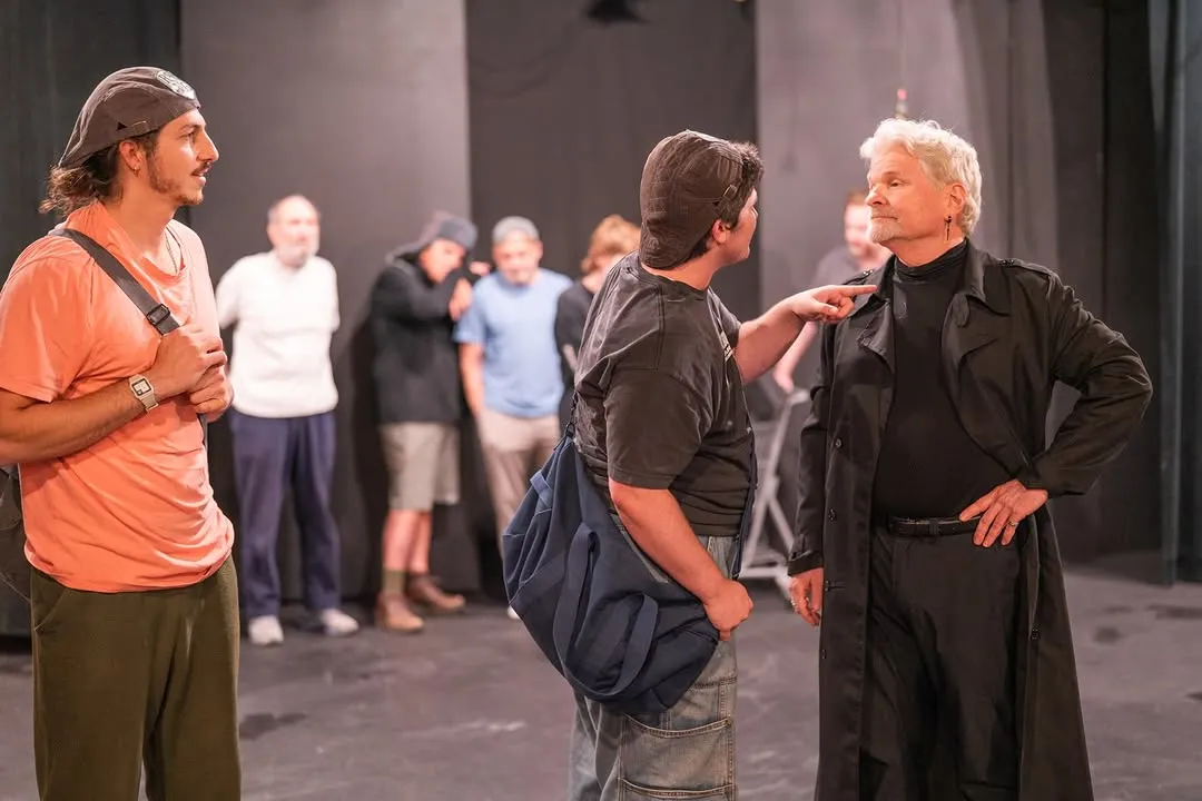 Cast members rehearsing together on stage in casual clothing.
