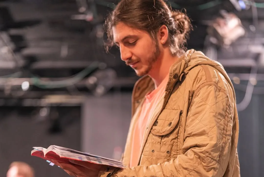 A performer reading a script during rehearsal.