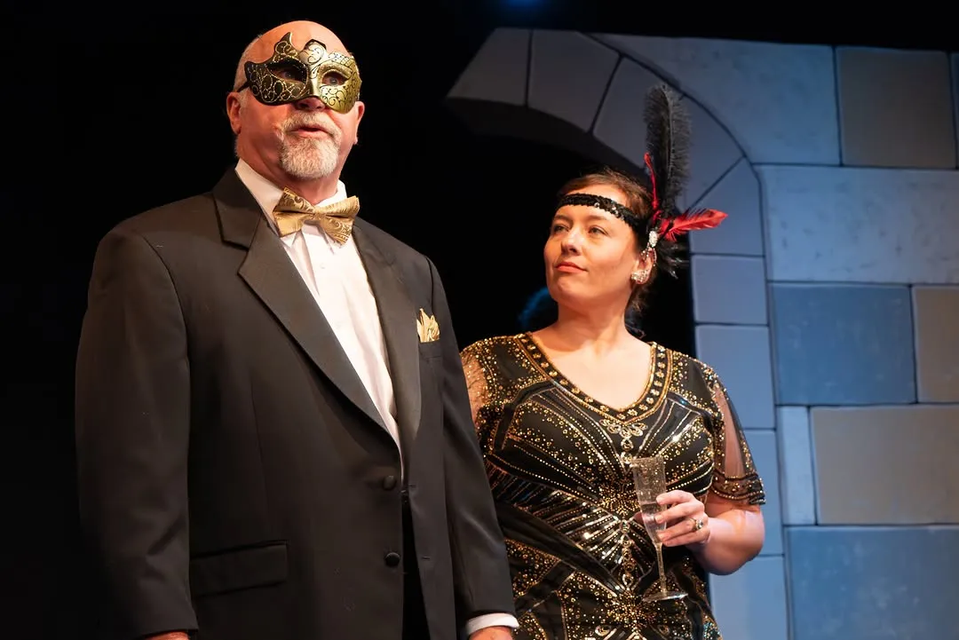 Two performers in court costumes and masks on stage.