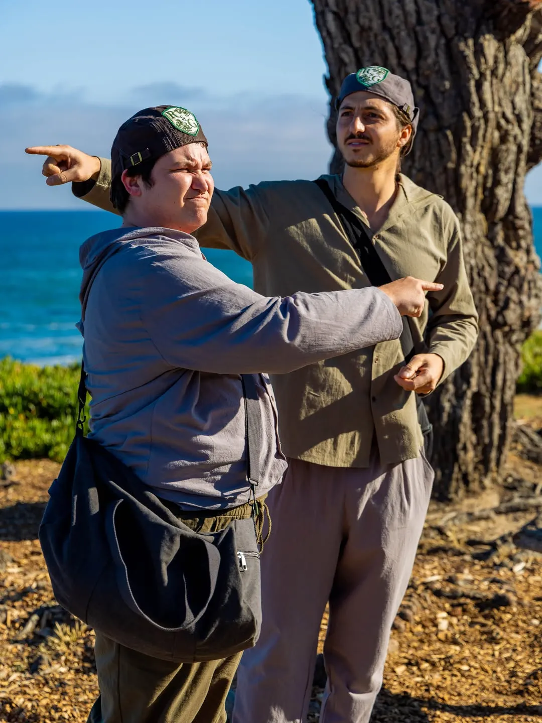 The two costumed leads outside, one pointing towards the other.