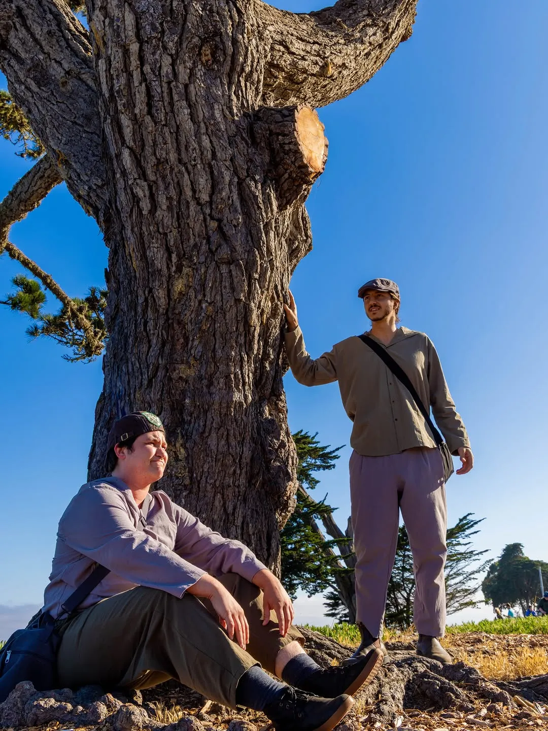 Two costumed performers beneath a tree.