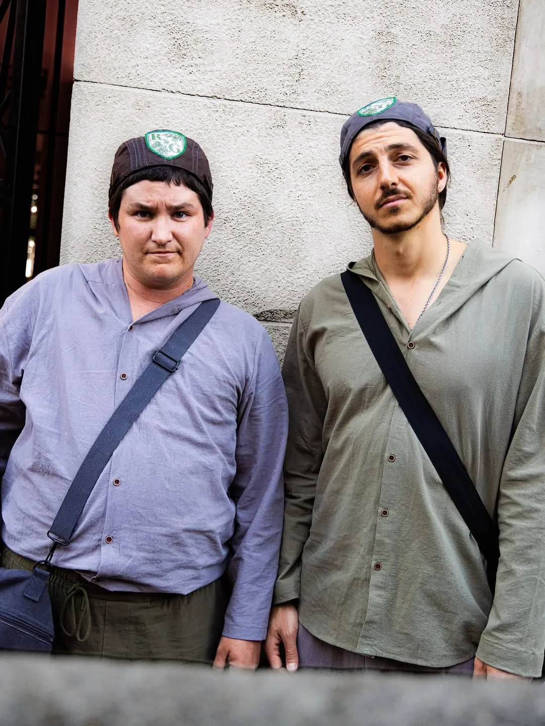 Rosencrantz and Guildenstern standing side by side against a wall.